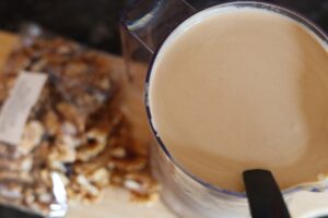 Coffee infused ice-cream base in a jug, next to the jug are some nuts on a chopping board. Implying you could choose to use this as a mix in, or leave it.